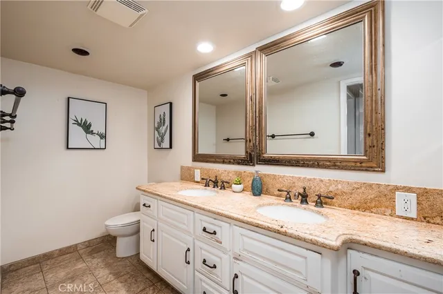 a bathroom with a granite countertop sink a toilet and a mirror