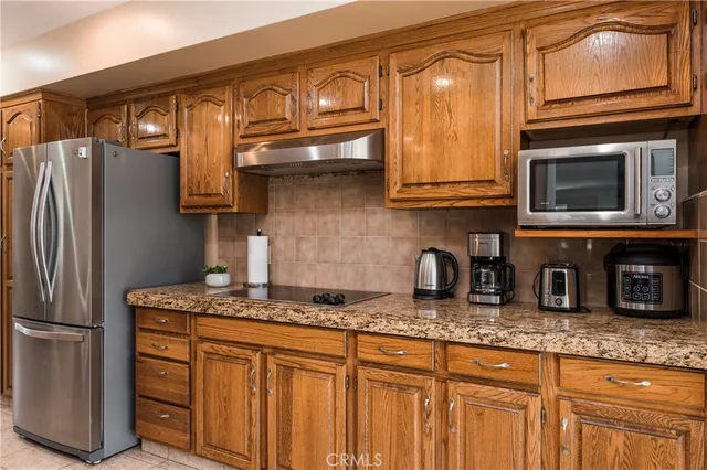a kitchen with granite countertop stainless steel appliances a stove refrigerator and cabinets