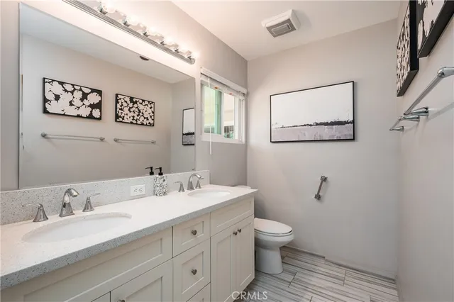 a bathroom with a granite countertop sink mirror vanity and toilet