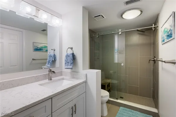 a bathroom with a shower sink vanity mirror and toilet
