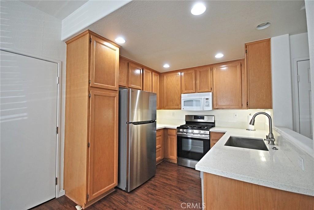 25745 Perlman Place, Unit A Stevenson Ranch, CA 91381 - Photo 9 of 28 a kitchen with kitchen island a counter top space stainless steel appliances and cabinets