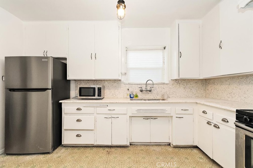 14248 Friar Street Van Nuys, CA 91401 - Photo 12 of 36 a kitchen with granite countertop a refrigerator sink stove and white cabinets