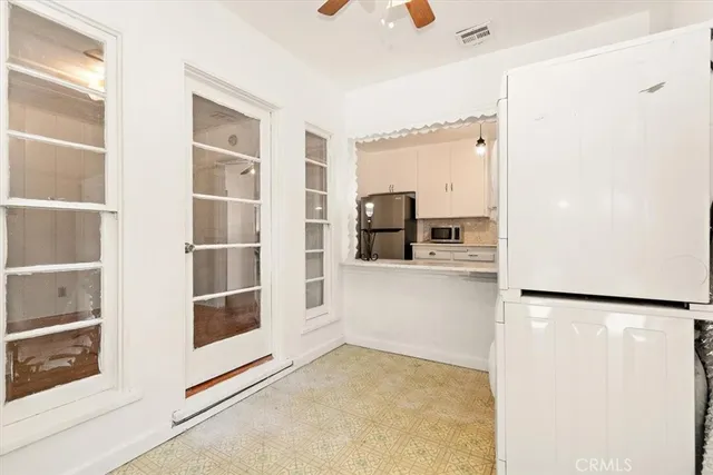 a view of a kitchen with white cabinets and window