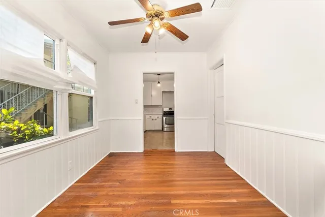 a view of empty room with wooden floor and fan