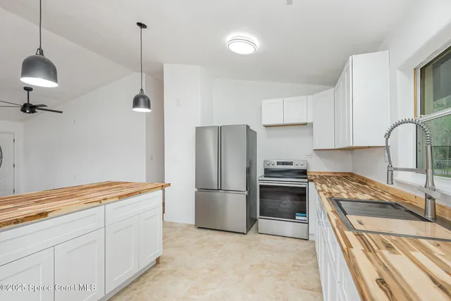 a kitchen with granite countertop a stove a sink and a refrigerator