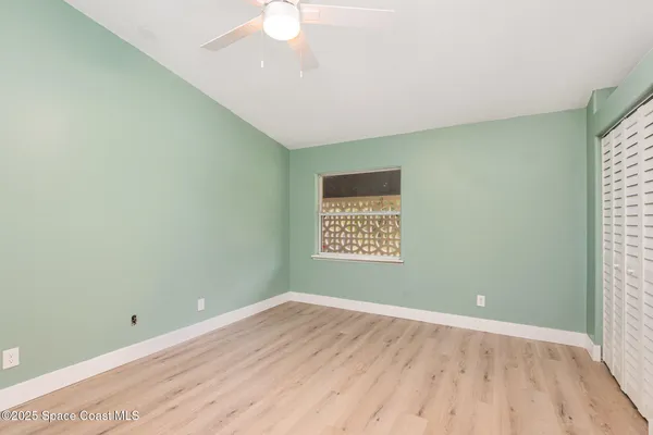 a view of an empty room with a window and wooden floor