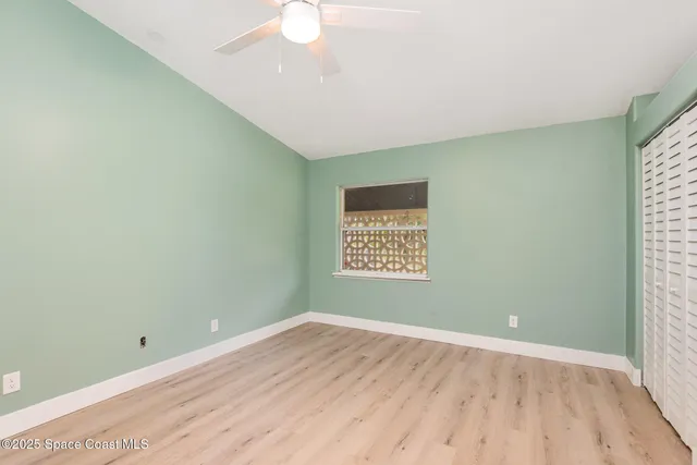 a view of an empty room with a window and wooden floor