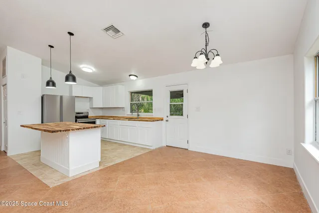 a view of a kitchen with stainless steel appliances granite countertop a sink a stove and white cabinets