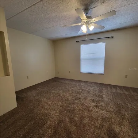 an empty room with a chandelier fan and windows