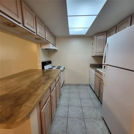 a kitchen with granite countertop a sink a stove top oven and refrigerator