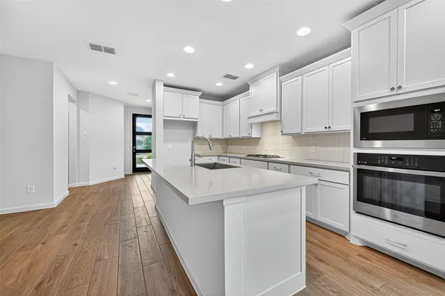 a kitchen with stainless steel appliances granite countertop a stove a sink and a microwave