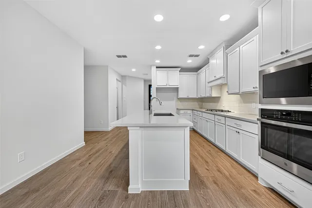 a kitchen with stainless steel appliances granite countertop a stove top oven a sink and a granite counter tops with wooden floors