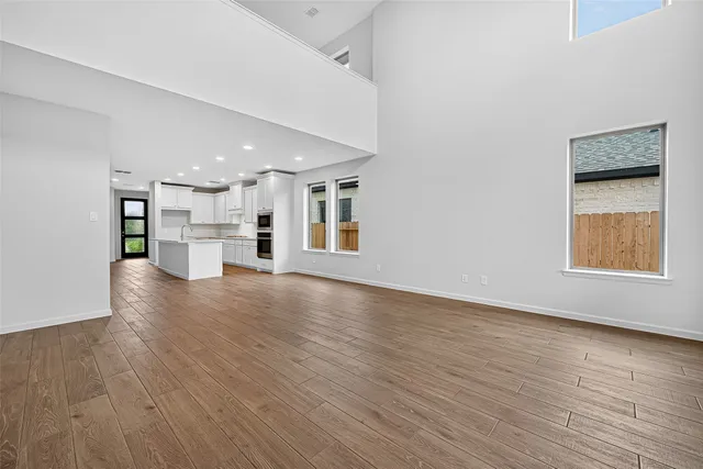a view of empty room with wooden floor and a window