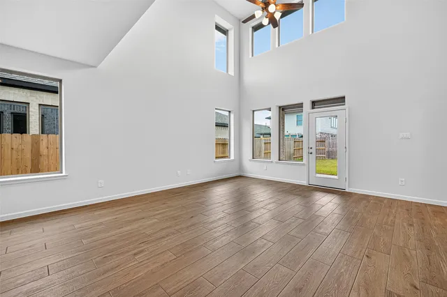 a view of an empty room with window and wooden floor