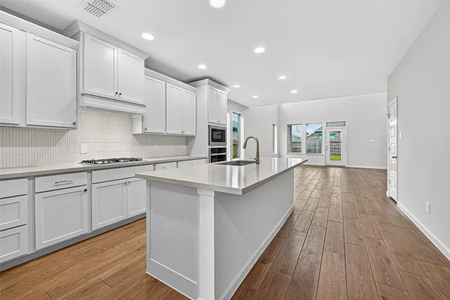 a kitchen with kitchen island granite countertop a sink cabinets and wooden floor