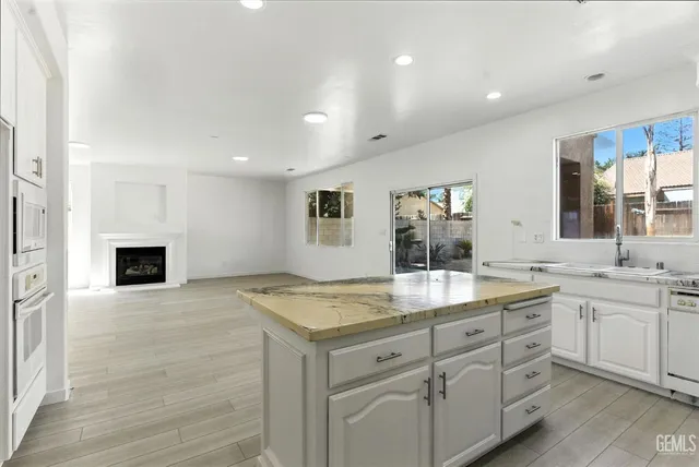 a hall with kitchen island a sink dishwasher a fireplace with wooden cabinets