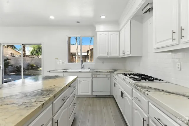 a kitchen with granite countertop a sink stove and cabinets