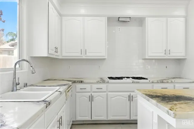 a kitchen with granite countertop white cabinets and a sink