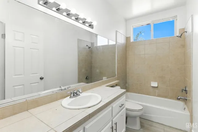 a bathroom with a granite countertop sink a toilet and shower