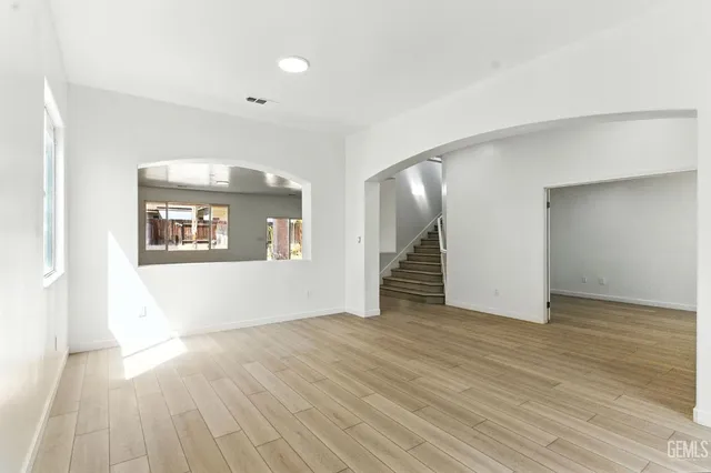 a view of an empty room with wooden floor and a ceiling fan