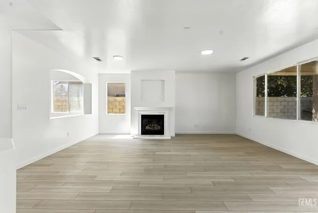 a view of an empty room with a window and fireplace