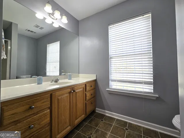 a spacious bathroom with a double vanity sink a large mirror and a window