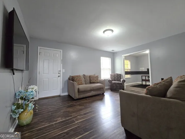 a living room with furniture a wooden floor and a flat screen tv