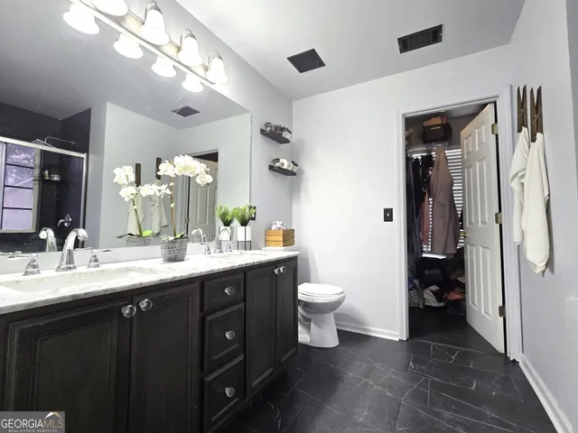a bathroom with a toilet sink double vanity and mirror