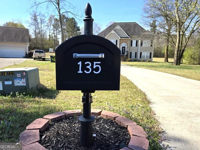 a sign board with a house and yard in the back