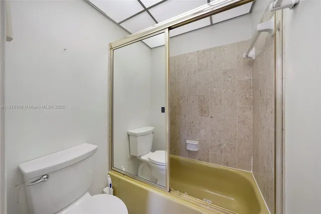 a bathroom with a granite countertop sink a toilet a mirror and shower