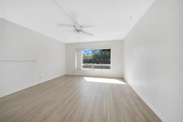 a view of an empty room with a window and a ceiling fan