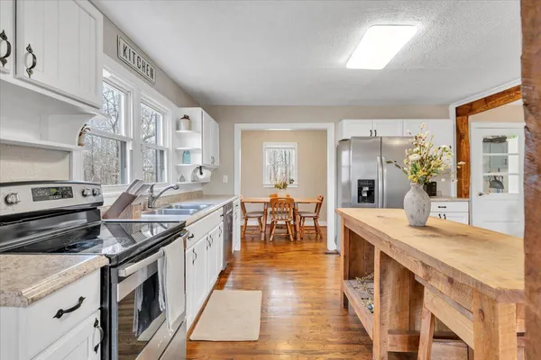 a kitchen with stainless steel appliances kitchen island granite countertop a refrigerator a stove and a sink with granite countertops