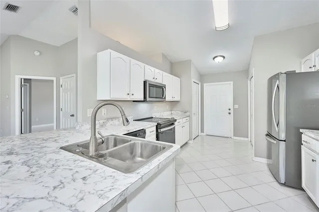 a kitchen with stainless steel appliances granite countertop a sink refrigerator and microwave