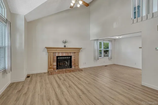 an empty room with wooden floor fireplace and windows