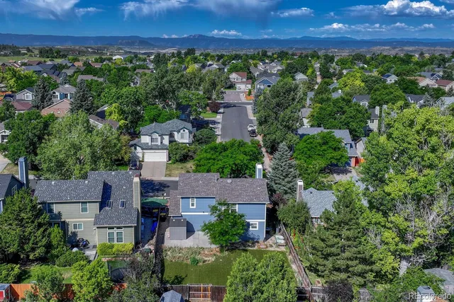 an aerial view of residential houses with outdoor space and trees
