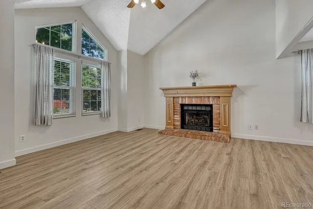 an empty room with wooden floor a fireplace and windows