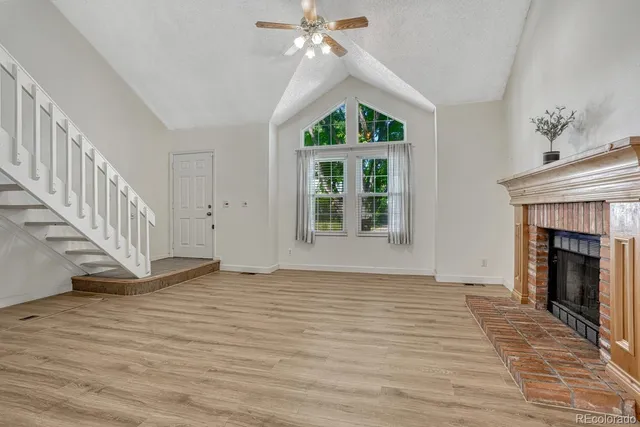 a view of an empty room with wooden floor fireplace and a window