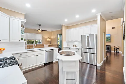 a kitchen with a refrigerator a stove top oven a sink and white cabinets with wooden floor
