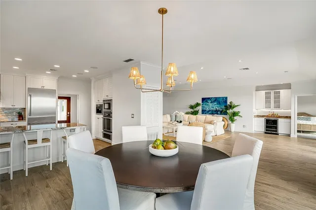 a view of a dining room and livingroom with furniture wooden floor a chandelier
