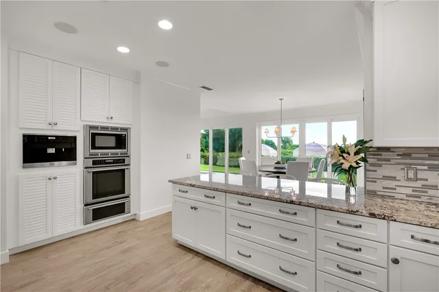 a kitchen with granite countertop white cabinets and stainless steel appliances