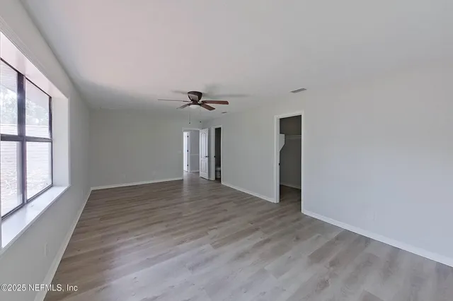 a view of empty room with wooden floor and fan