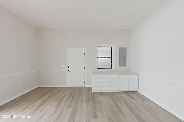 a view of empty room with wooden floor and fan