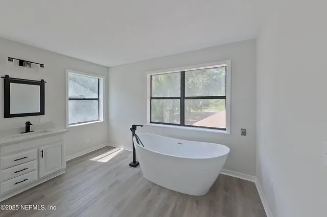 a bathroom with a white tub a sink and window
