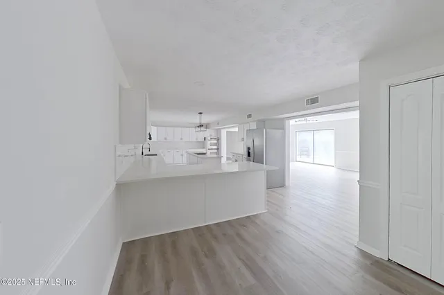 a large white kitchen with kitchen island white cabinets and wooden floor