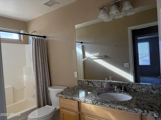 a bathroom with a granite countertop sink toilet and shower