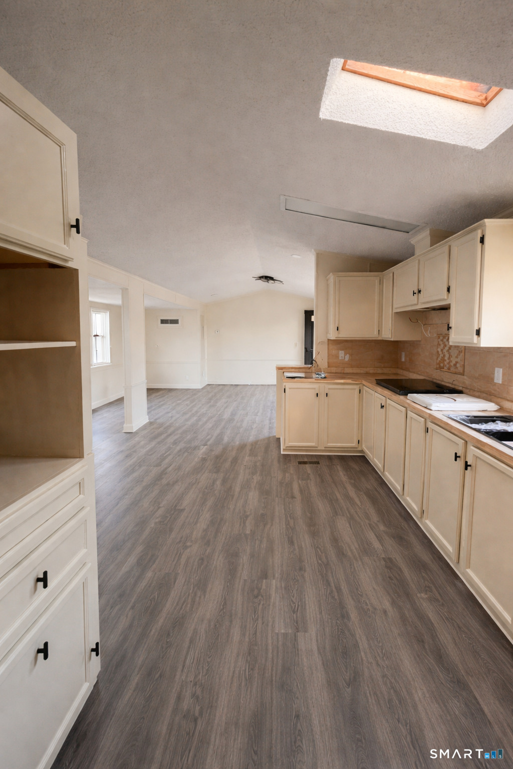 a large kitchen with a wooden floor and white stainless steel appliances