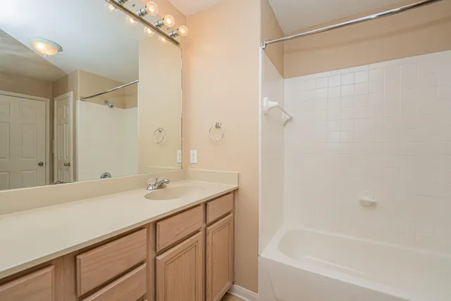 a bathroom with a granite countertop sink mirror and a bathtub