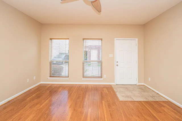 an empty room with wooden floor and windows