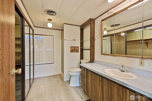 a bathroom with a granite countertop sink a toilet a mirror and shower