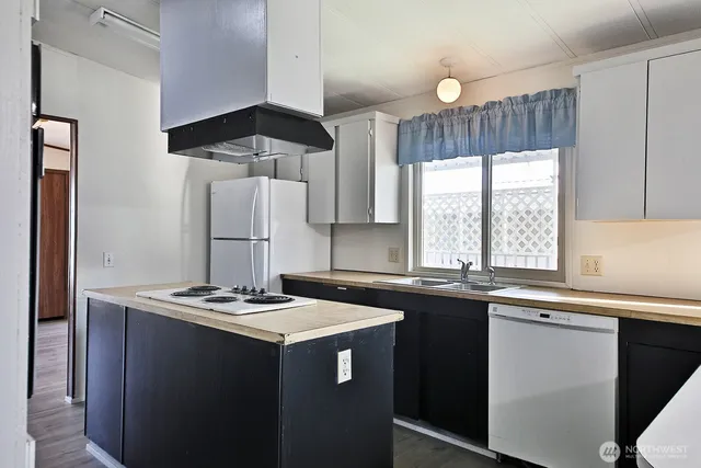 a kitchen with kitchen island granite countertop a sink stove and refrigerator